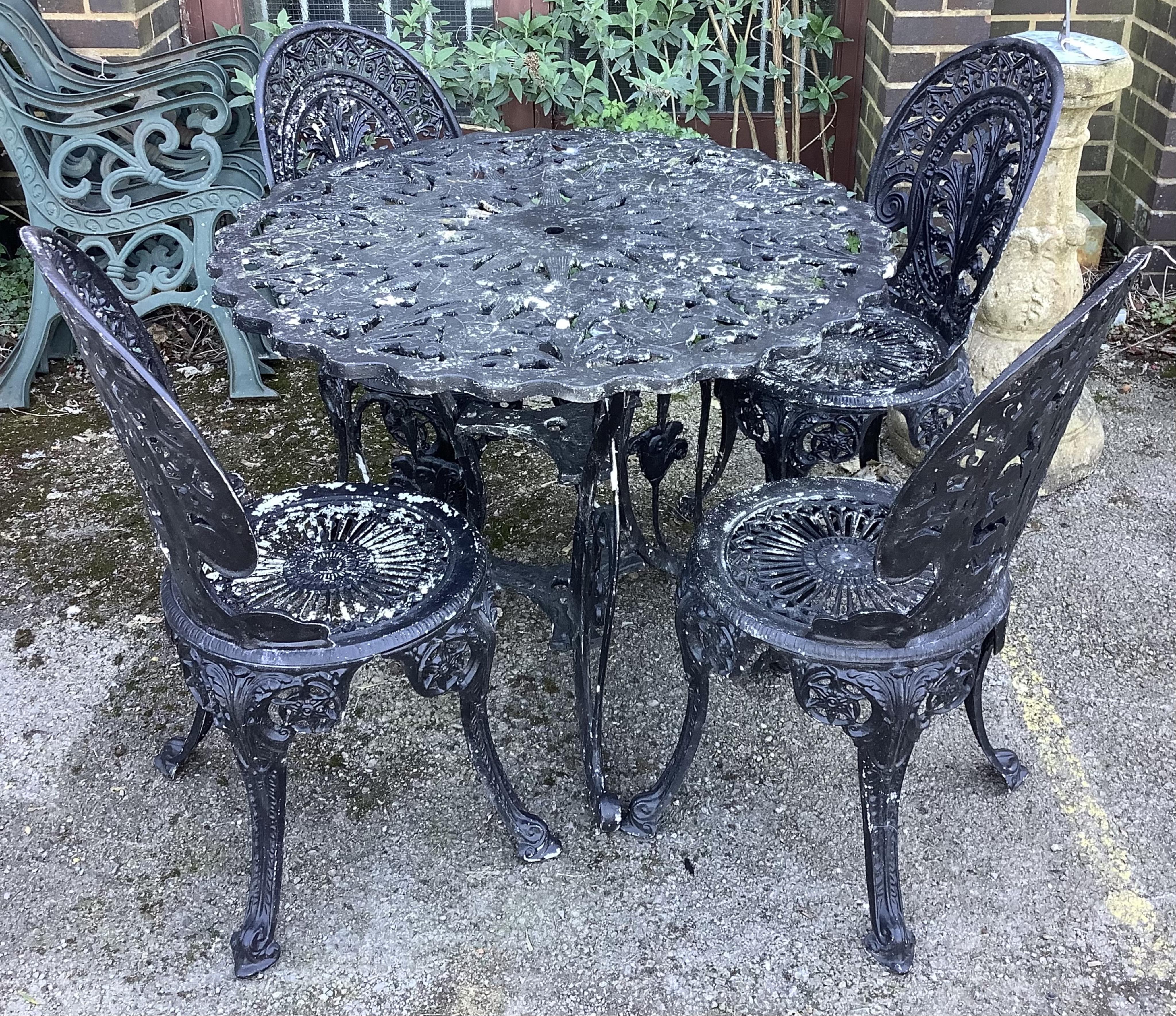 A Victorian style circular cast metal garden table, diameter 89cm, height 70cm together with four chairs. Condition - fair